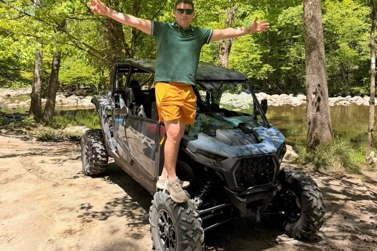 Renter standing on a street-legal UTV beside a Smoky Mountains river